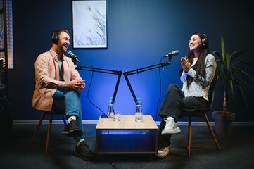 Side view of successful woman hosting podcast interviewing man while recording with professional...