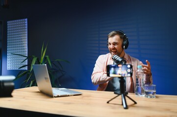 vlogger using smartphone to film podcast in studio. blogger with mobile phone, microphone and...