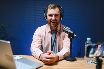 A video blogger records content in his studio. The host of the video blog is a young man who is...