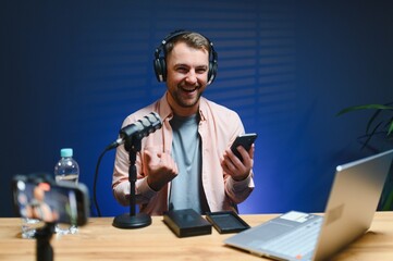 A video blogger records content in his studio. The host of the video blog is a young man who is...
