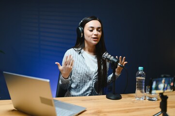 Positive female vlogger recording a video on camera sitting at desk