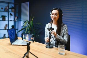 Positive female vlogger recording a video on camera sitting at desk