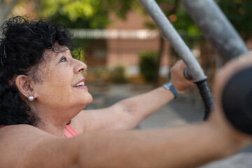 Senior hispanic woman exercising and lifting weights outdoors