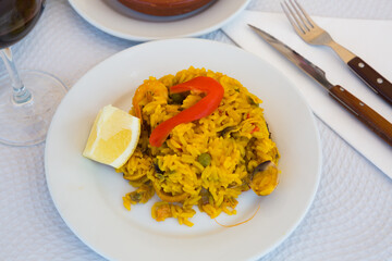 Paella with shrimp, pepper, vegetables and lemon on platter. High quality photo