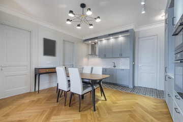 Modern design of the kitchen dining room in the apartment. Light blue kitchen set with built-in appliances.
