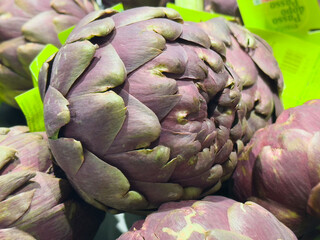 Fresh purple artichokes displayed in a market setting showcasing their unique texture and vibrant color, emphasizing healthy eating concept