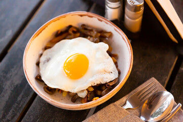 Delicious country style lunch of homemade fried potatoes with onion and mushrooms served with sunny side up egg..