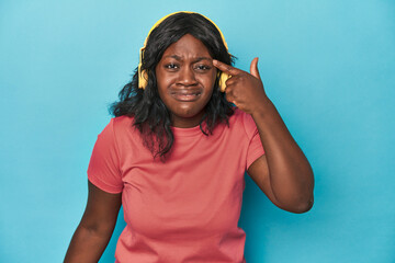 Naklejka premium Curvy lady enjoying music in studio showing a disappointment gesture with forefinger.