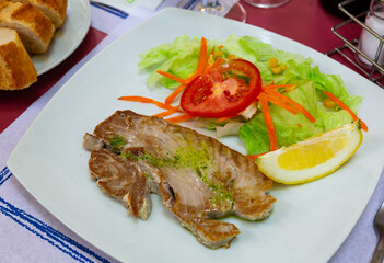 Scandinavian cuisine seafood served with greens and vegetables on plate on wooden table
