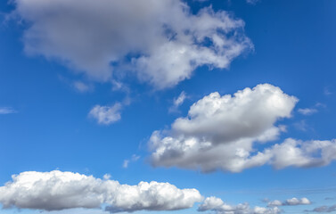 A vast blue sky with scattered clouds forms a dreamy, calm scene. The clouds vary in size and...