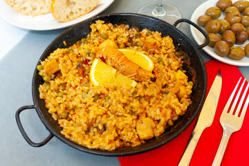 Tasty Valencian paella marinera with shrimps and scallop served with lemon on iron frypan