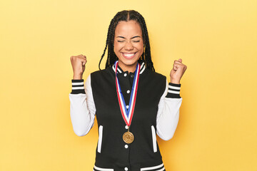 Indonesian student girl showcasing her medal on yellow studio backdrop