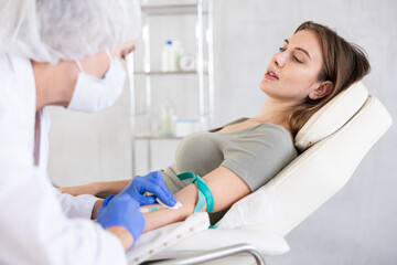 Fototapeta premium Young long-haired girl lying at white examination couch before intravenously injection at treatment room