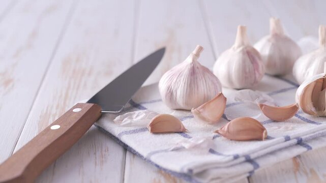 Garlic bulbs and garlic cloves on a white wooden table .