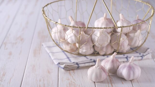 whole garlic bulbs in a metal basket on a kitchen wooden table. garlic bulbs in a metal basket on a white wooden table.