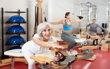 Senior female during Pilates training performs exercises and tasks on heron pulley tower for...