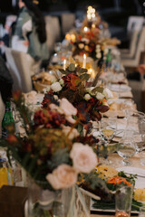 Elegant dinner table with floral centerpiece and candles outdoors.
