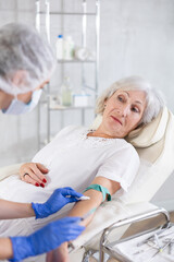 Obraz premium Adult woman with grey hair is receiving injecting hypodermic against covid or flu.