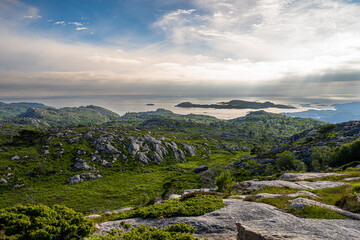 rocky coastal landscape with distant islands and dramatic sky.