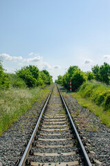 Obraz premium Straight railway track in a green landscape under a blue sky