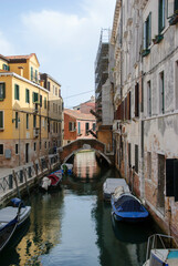Narrow Venetian canal with boats and historic buildings