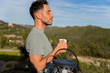 Happy man drinks coffee outdoors meditating and enjoying views and fresh air
