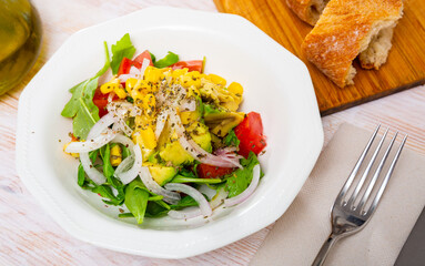 Plate of low calorie salad with fresh tomatoes, avocado and arugula