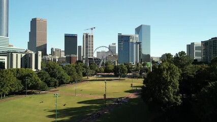 Aerial rising reveal shot of Centennial Olympic Park and Atlanta skyline. Expansive 2026 football tournament fan zone and downtown convention district.