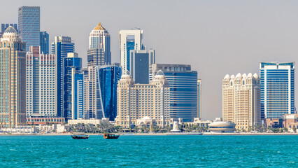 Obraz premium Doha modern business downtown center skyscrapers shoreline with small traditional arab dhow fishermen boats at the sea bay, Qatar