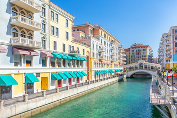 Obraz premium Qanat Quartier Venetian copy luxury residential district with authentic colorful apartment buildings and water channel with bridge, Pearl Island, Doha, Qatar