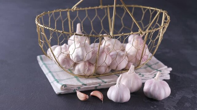 whole garlic bulbs in a metal basket on a black stone table. garlic bulbs in a metal basket on a black table.
