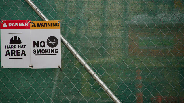 signs at a construction site. No smoking and you need a hardhat