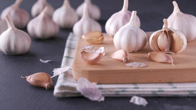 Garlic bulbs and garlic cloves on a black stone table. 
organic garlic on a black table.