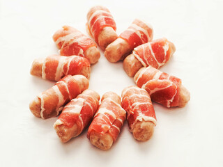 Pigs in blanket in round shape on white background. Classic British style snack food. Small sausages wrapped in bacon slices.