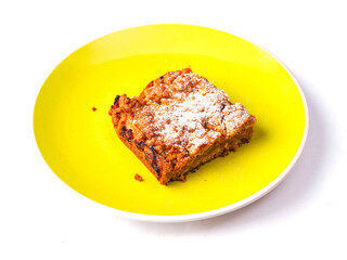 A yellow plate with a piece of cake on it. The cake is covered in powdered sugar. The plate is placed on a white background. Premium slice of a fine bakery product