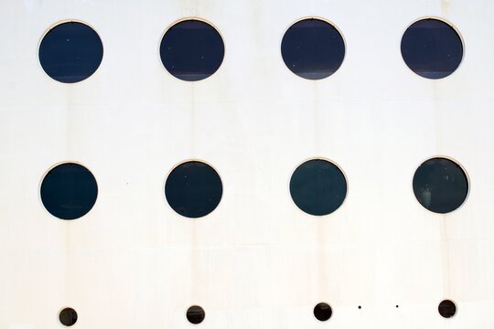 Round windows of different sizes on the side of a large ship