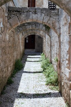 Cobblestone street of a medieval town with stone arches