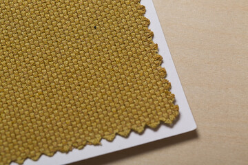 Golden yellow fabric swatch texture close-up on a birch wood panel for background or design element