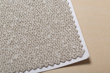 White beige gray sand boucle fabric swatch texture close-up on a birch wood panel for background or design element