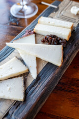 Tasting of Spanish cheeses made on Canary islands, goat cheese, smoked and triangles of manchego curado cheese on wooden plank