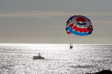 Parasailing or parascending recreational water sport with boat on Tenerife, Costa de Adeje, adventure for tourists