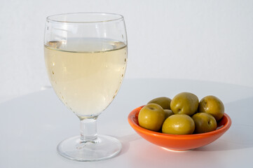 Spanish dry rueda white wine and green olives tapas on white table