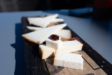 Tasting of Spanish cheeses made on Canary islands, goat cheese, smoked and triangles of manchego curado cheese on wooden plank