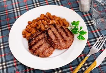Appetizing roasted beef burger patty served with beans on platter