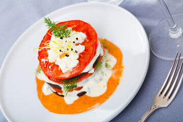 Grilled eggplant and tomatoes stack seasoned with spicy cream-tomato sauce served on white plate