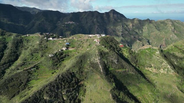 Stunning aerial view of a small village nestled in lush green mountains, overlooking a vast ocean. Perfect for travel, nature, and real estate projects. Anaga park.Tenerife.Spain