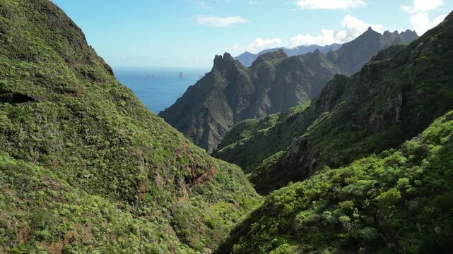Stunning panoramic view of a dramatic coastal mountain range. Lush green hills meet rugged cliffs overlooking the ocean. Perfect for travel, nature, or adventure projects. High-resolution image.Anaga