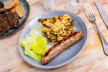 Delicious scrambled eggswith wild mushrooms and champignons with sausages