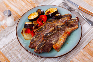 on wooden table plate with grilled beef ribs with fried vegetables-aubergine, pepper,onion.Traditional Spanish dish-churrasco.Top view