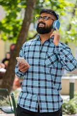 Happy overjoyed Indian bearded man dancing in wireless headphones listening favorite energetic...